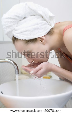 Young woman washing face, side view