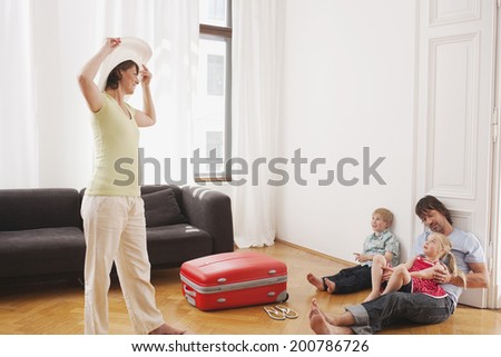 Father and children sitting on floor mother trying hat on