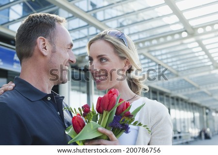 Germany, Leipzig-Halle, Airport, happy couple man giving woman bunch of flowers