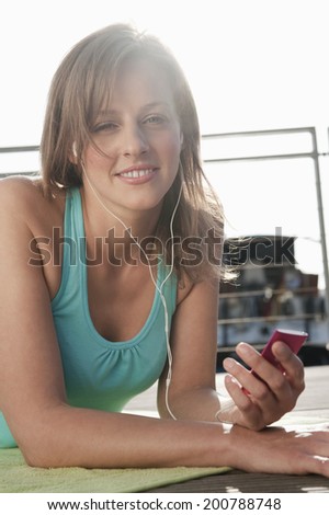 Germany, Hamburg, Woman lying on sun deck listening to music