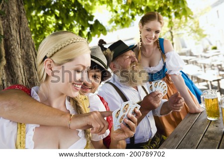 Germany, Bavaria, Upper Bavaria, people in traditional costume playing cards in beer garden