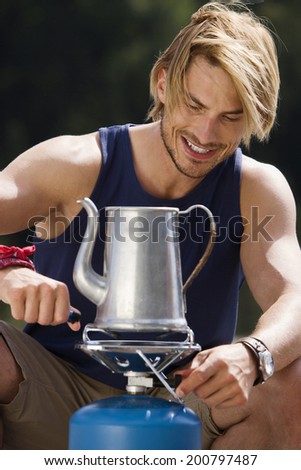 Germany, Bavaria, blond man lighting camp stove close-up