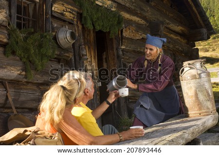 Peasant woman serving couple at alpine hut