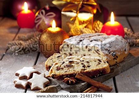 Christmas stollen on wooden board with candles christmas bulbs cinnamon stars cinnamon sticks pine twig present