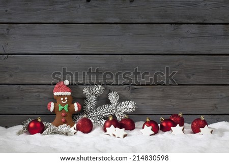 Christmas gingerbread bear christmas bulbs cinnnamon stars pine twig on pile of snow against wooden wall