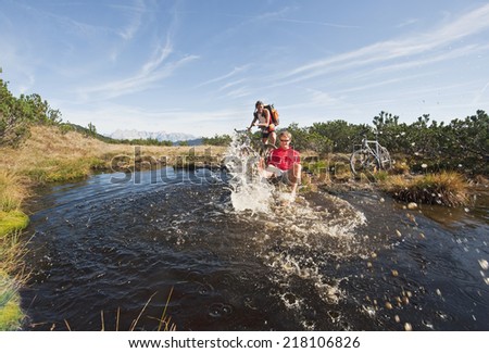 Austria, Salzburger Land, Bikers by lake, man splashing water, laughing, portrait