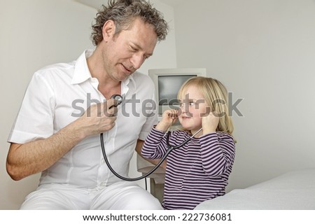 Young girl listening with stethoscope to doctor\'s heartbeat