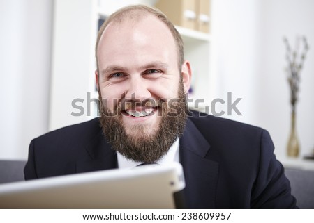 Businessman sitting on couch, reading on digital tablet