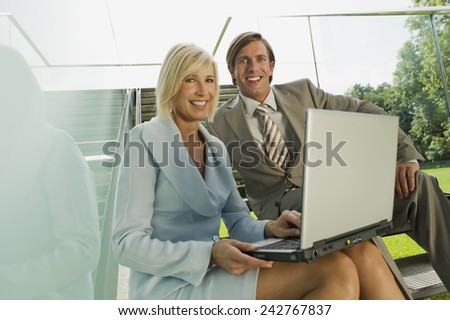 Germany, two business people using laptop