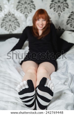 Teenage girl sitting on bed, wearing striped socks
