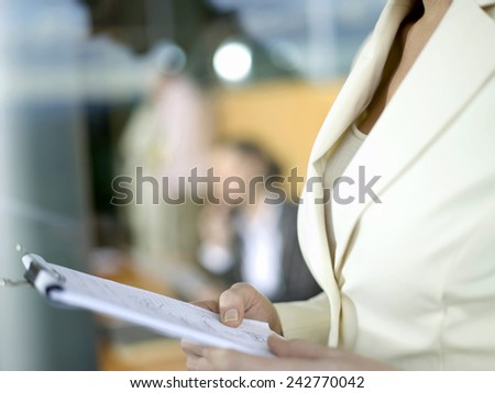 Young businesswoman holding writing pad, close-up
