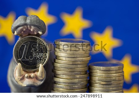 Euro coin in mouth of hippo figurine, EU flag