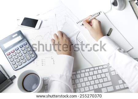 Stockbrocker working at desk, writing on notepad