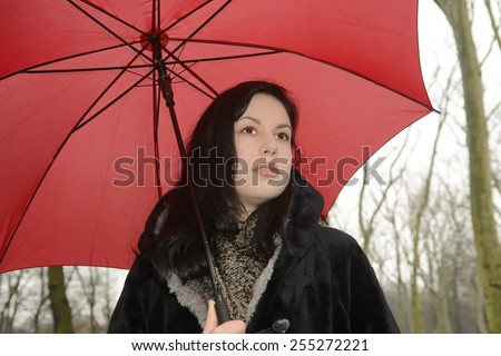 Germany, Berlin, thoughtful young woman with red umbrella