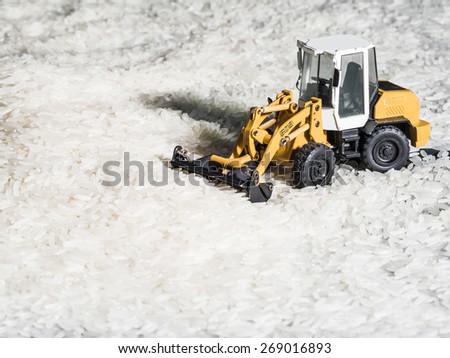 Toy digger on pile of rice, staple, distribution, trade