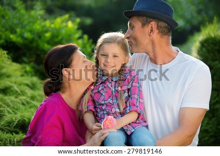 Girl with father and granny in garden, kissing
