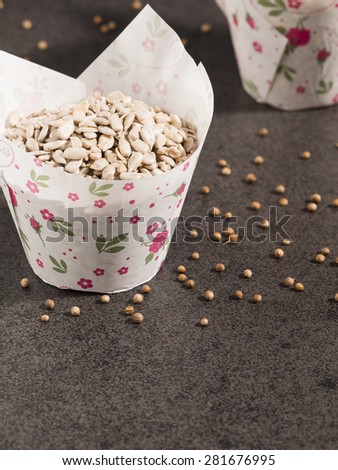 Sunflower seeds in paper form and coriander on dark background