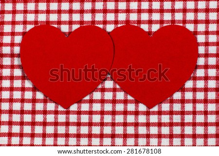 Two red hearts on red white checked cloth