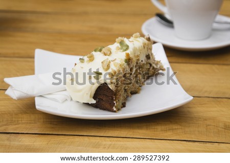 Piece of carrot cake with pumpkin seeds and walnuts on plate