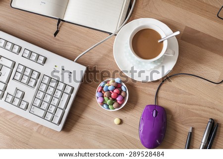 Cup of coffee and bowl with chocolate drops, workplace