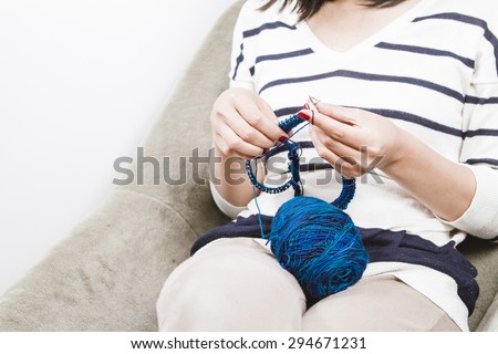 Woman knitting blue scarf with blue wool