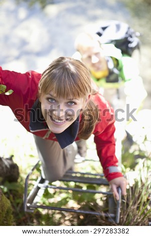 Germany,Upper Bavaria,Couple climbing ladder while hiking,smiling