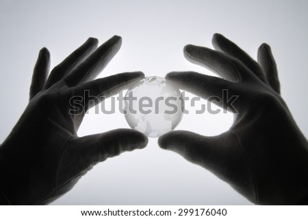 Human hand with cotton gloves holding glass globe against white background,close up