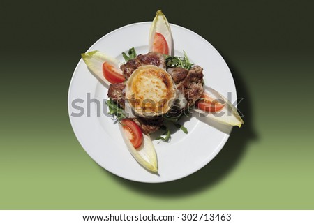 Pork steak with baked goat cheese and honey in plate