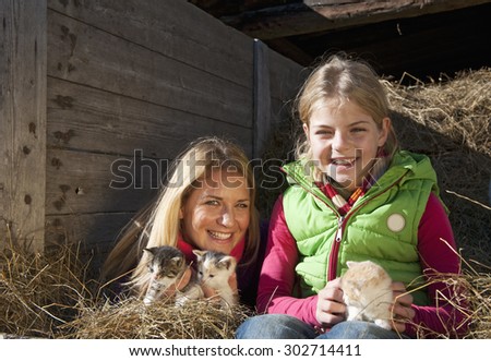 Austria,Salzburg Country,Flachau,Woman and girl holding kitten in hay trailer