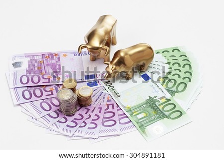 Golden bear and bull figurines with euro coins on fanned euro notes