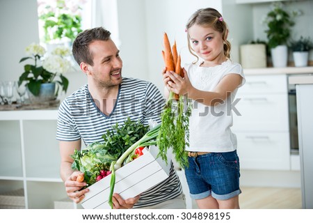 Father and daughter with vegetable box in kitchen