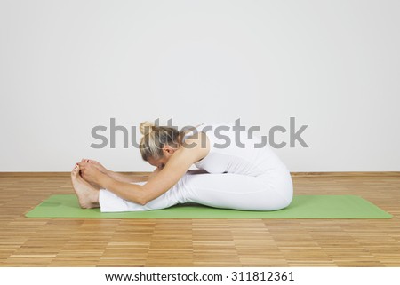 Woman practicing Yoga, seated forward bend, Paschimottanasana