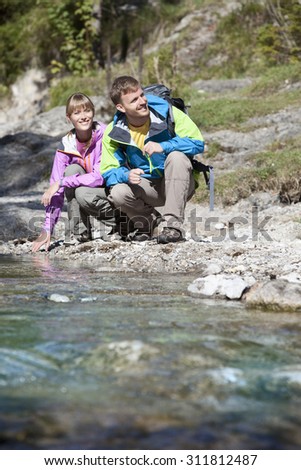 Germany,Upper Bavaria,Couple crouching near stream while hiking,smiling