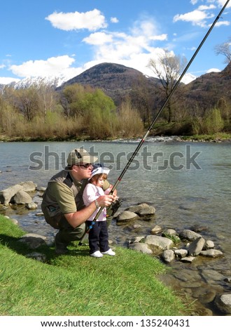 father and daughter fishing on river on summer day