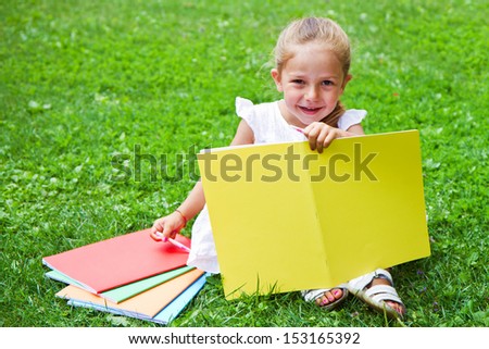 Girl drawing on book on the grass