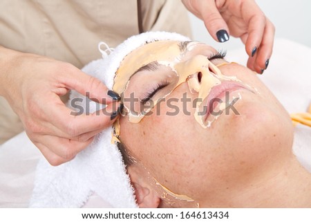 Beautiful young woman remove  facial mask  in a beauty center