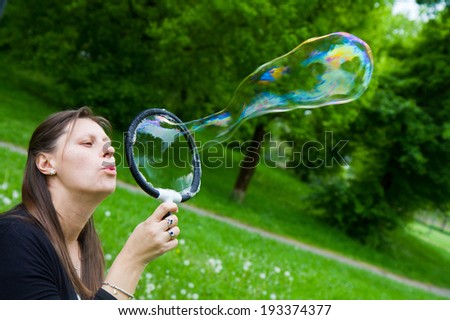 woman inflating colorful soap bubbles in spring park