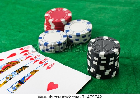 Poker chips and cards isolated against green felt