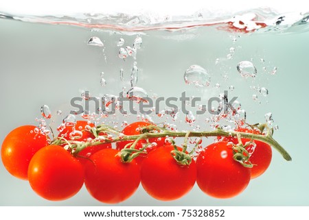 tomatoes splashing into water with a grey background