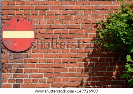 no entry road sign on a brick wall and green bush