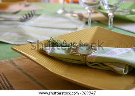 Yellow plate in a table with dinnerware.