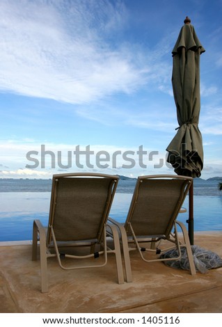 Some chairs on a beach front pool waiting for you to sit on them