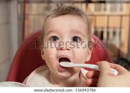 Mother feeding her baby girl with full of formula spoon