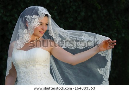 Bride holding open her bridal veil with her finger