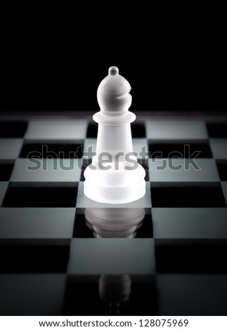 Glass bishop chess piece over black background