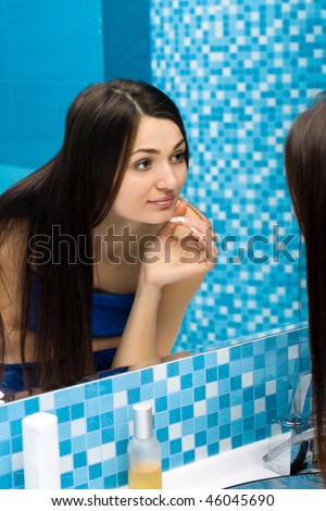 Beautiful woman in bathroom behind the mirror