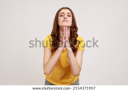 Please, I'm begging forgive! Adorable upset worried woman of young age with wavy hair looking with imploring desperate grimace, praying for help. Indoor studio shot isolated on gray background. Imagine de stoc © 