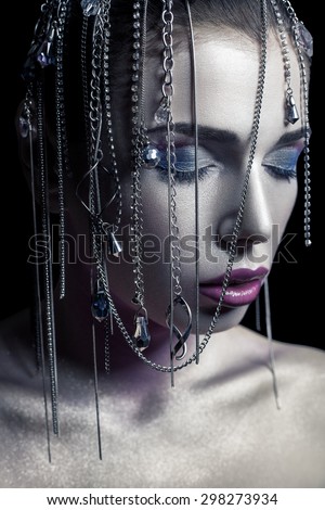 Different style of beauty. young beautiful fashion model with silver, purple, blue makeup and shiny silver jewelry chain on her face. studio low key shot. retouched with special care and attention.