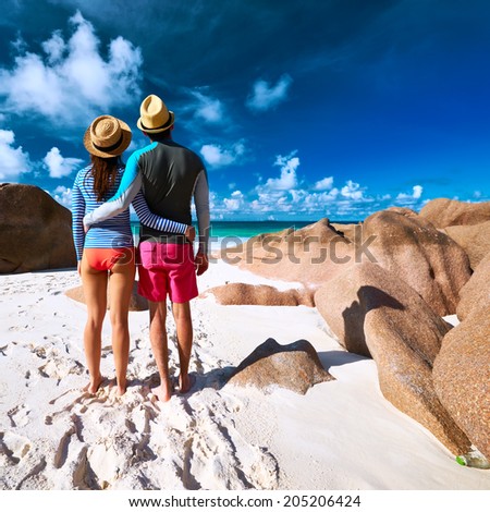 Couple on a tropical beach at Seychelles wearing rash guard