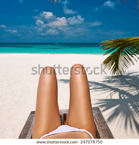Woman at beautiful beach lying on chaise lounge